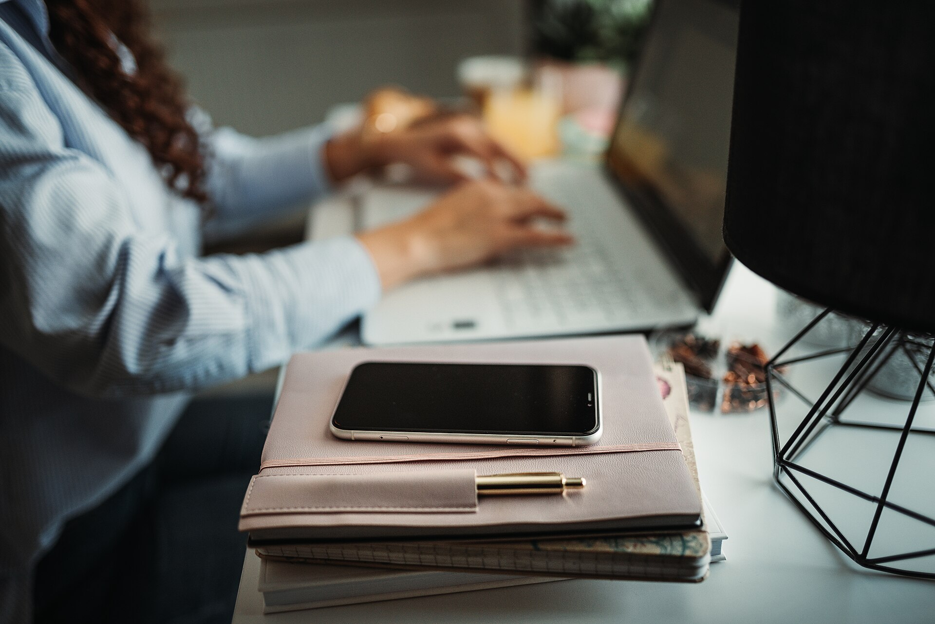 Persona estudiando un idioma con su tel&eacute;fono y una laptop sobre el escritorio